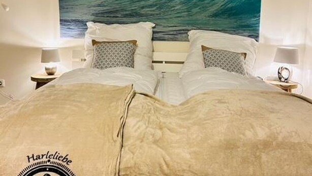 Een slaapkamer met een groot bed, twee nachtkastjes en een muurschildering van een golf.