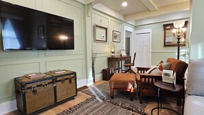 A living room with a television, a wooden chest, a dining table with chairs, and a sofa. - Stay Downtown in one of Princeton's historical homes, The Burr House (Princeton)
