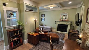 A living room with a fireplace, a bookshelf, a sofa, and a dining table. - Stay Downtown in one of Princeton's historical homes, The Burr House (Princeton)