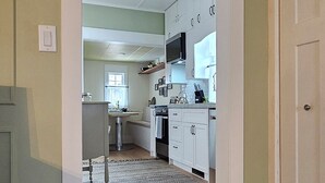 A hallway leading to a kitchen with wooden flooring, a rug, and white cabinets. - Stay Downtown in one of Princeton's historical homes, The Burr House (Princeton)