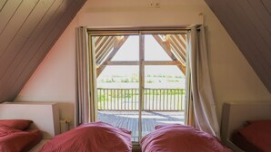 A bedroom with two beds, a large window with curtains, and a view of a garden. - Villa Haut Briauche (61) - Heated pool - Beach Volley - 2h Paris - 45p (Eperrais)