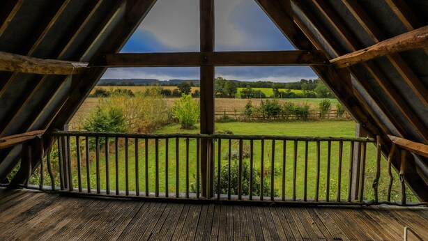 An attic room with a wooden floor and a metal railing overlooking a green field. - Villa Haut Briauche (61) - Heated pool - Beach Volley - 2h Paris - 45p (Eperrais)