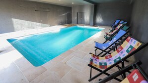 Une piscine dotée de chaises longues et d’un sol carrelé.