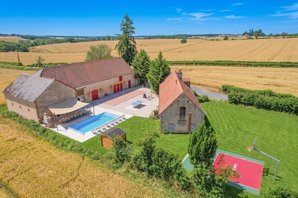 A large house with a swimming pool, a tennis court, and a well-maintained lawn.