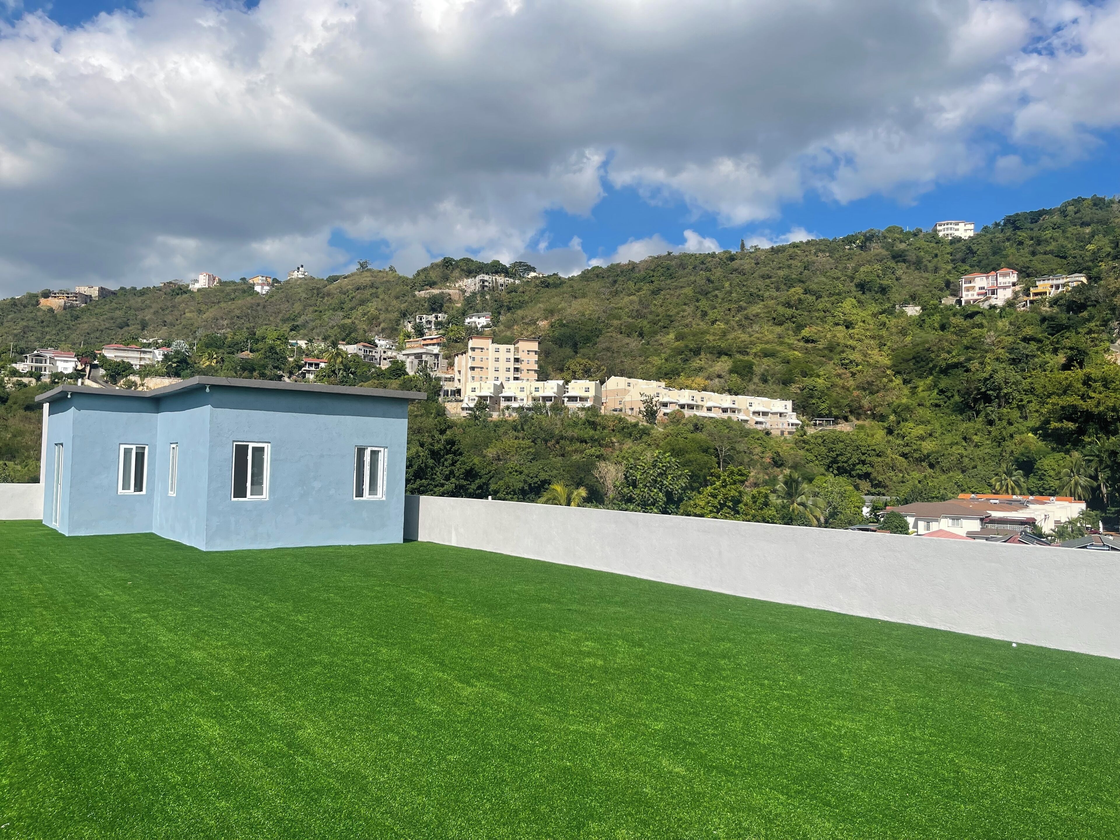A small blue building with a flat roof, surrounded by a well-maintained green lawn.