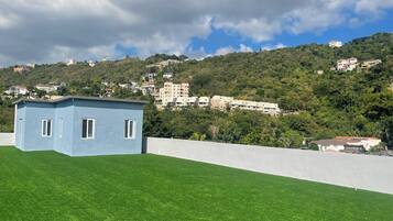 A small blue building with a flat roof, surrounded by a well-maintained green lawn.