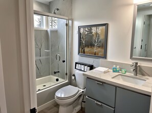A modern bathroom with a glass-enclosed shower, a toilet, a sink with toiletries, and a framed painting on the wall. - Charming 4-bedroom Townhouse in pleasant Los Angeles FREE AC, WiFi and Parking (Los Angeles)