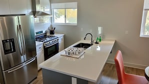 Una cocina moderna con electrodomésticos de acero inoxidable, una isla central y un ventanal que proporciona luz natural.