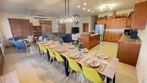 Un vaste espace de vie comprenant une salle à manger avec une table dressée, une cuisine dotée de meubles en bois et un coin salon avec un canapé et des fauteuils.
