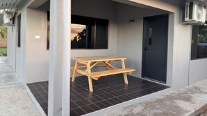 A modern building with a covered outdoor area, a wooden bench, and a door. - Dovu Residences (Labasa)