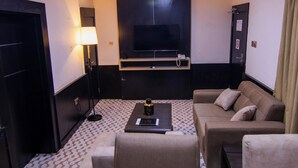 Une chambre d’hôtel avec un canapé, une table basse, une télévision, une lampe et une porte.