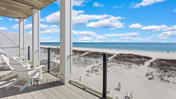 Vista de la playa desde una terraza techada con sillas blancas y techo de madera.