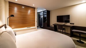 A modern hotel room with a large bed, a desk, a chair, a TV, and a wardrobe. - THE SKY HOTEL (Cheonan)