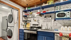 Eine Küche mit Waschmaschine, Backofen, Spüle und verschiedenen Küchengeräten.
