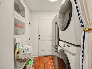 Een wasserette met een deur, een wasmachine en een droger.