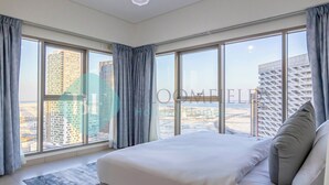 A modern bedroom with a large bed, a view of the cityscape, and a city view through the windows.