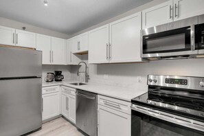 A modern kitchen with white cabinets, stainless steel appliances, and a built-in microwave.