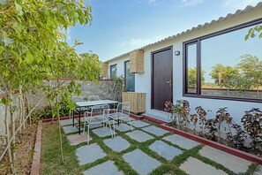Eine Terrasse mit Steinplattenboden, umgeben von einer niedrigen Ziegelmauer und verschiedenen Pflanzen.