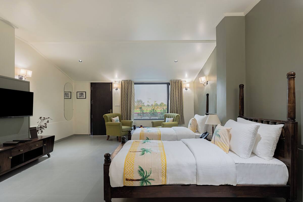 Une chambre d’hôtel avec un grand lit, une télévision, un bureau et une fenêtre avec des rideaux.