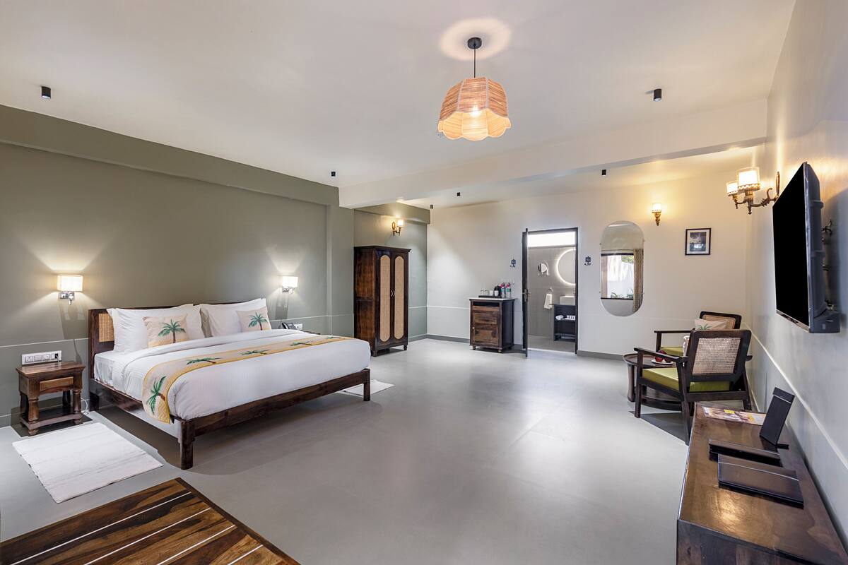 Une chambre d’hôtel moderne, dotée d’un grand lit, de tables de chevet, d’un bureau et d’une chaise.