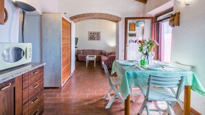 Une cuisine compacte équipée d’un four à micro-ondes, de meubles en bois et d’un coin repas avec une table dressée pour deux personnes.