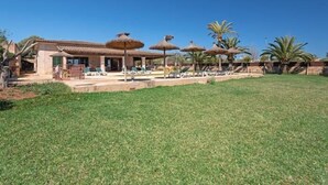 A resort with a pool area, lounge chairs, and thatched umbrellas. - Charming finca with large pool and garden in Santanyi for up to 8 persons (Santanyi)