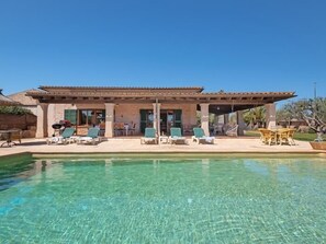 Un espace aménagé au bord de la piscine, avec des chaises longues, un patio couvert et une piscine à eau claire.