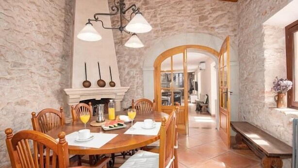 A dining area with a stone wall, wooden furniture, and a fireplace. - Incredible finca with huge garden and pool for up to 8 persons in Santanyi (Santanyi)