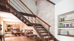 A spacious living area with a wooden staircase, a fireplace, and a bookshelf. - Incredible finca with huge garden and pool for up to 8 persons in Santanyi (Santanyi)