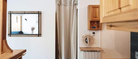 A room with a wooden cabinet, a mirror, a curtain, and a decorative item on a shelf.
