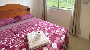 A bedroom with a bed, a painting of the Colosseum, a window with curtains, and a ceiling light. - Coconut Inn (Moalboal)