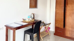 A room with a wooden desk, a chair, a wardrobe, and a small table with a kettle and water bottles. - Coconut Inn (Moalboal)
