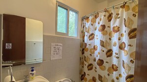 A bathroom with a toilet, sink, and a window. There is a sign on the wall and a shower curtain with a shell pattern. - Coconut Inn (Moalboal)