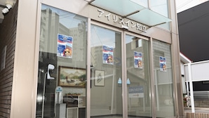 A building with large glass doors and windows, signage above the entrance, and several posters on the glass. - Iris in Chiryu (Chiryu)
