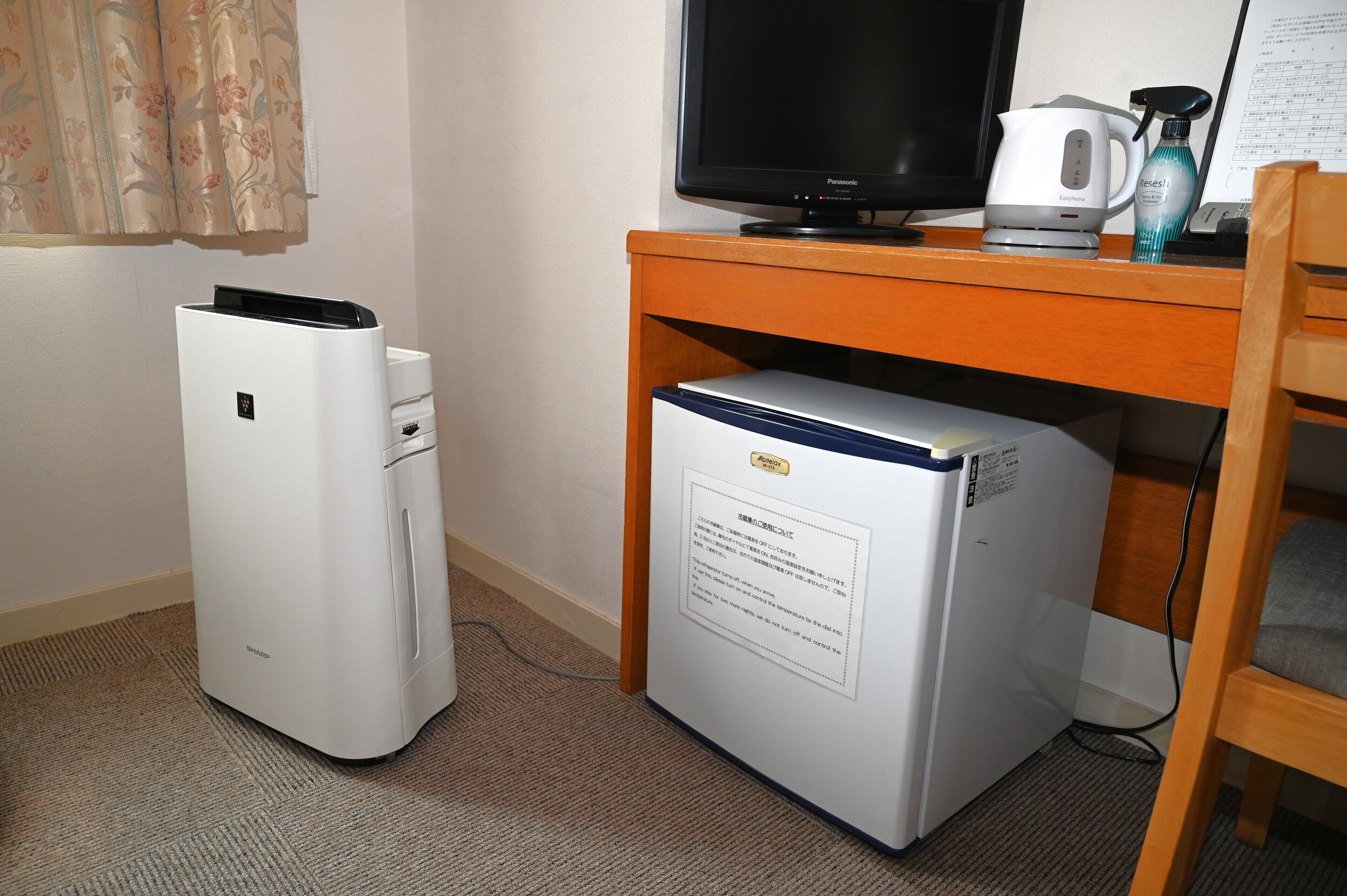 Una kitchenette pequeña con refrigerador, microondas y cafetera sobre una encimera de madera.