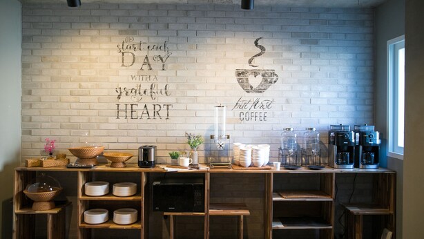 A cafe with a white brick wall, coffee machines, and shelves with bowls and cups. - Gray Boutique hotel (Tongyeong)