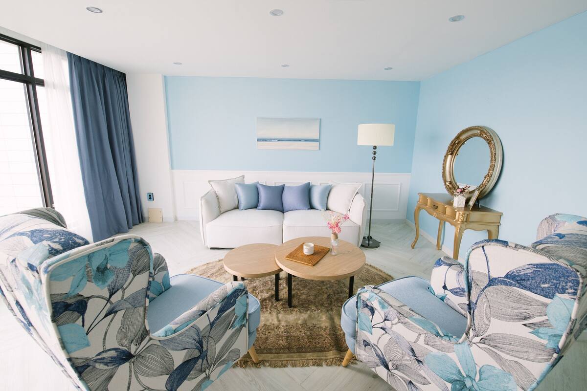 A living room with a sofa, two armchairs, a coffee table, a floor lamp, and a mirror.