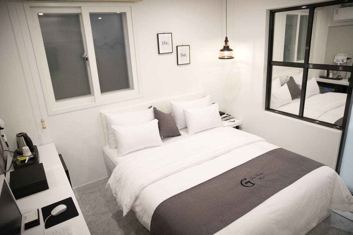 A neatly arranged bedroom with a bed, bedside table, and a desk with a computer.