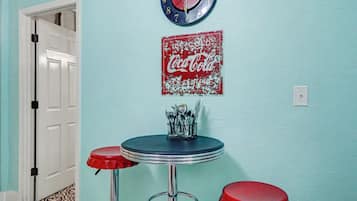A room with a Coca-Cola clock, a vintage Coca-Cola sign, and two red bar stools.
