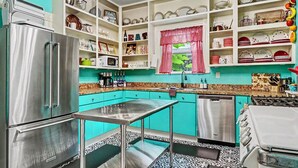 A kitchen with teal cabinets, a stainless steel refrigerator, and a patterned floor. - Walk to Bathhouse Row! Queen Anne Victorian Cottage (Hot Springs)