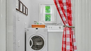 A laundry room with a washing machine, dryer, and a window with a view of greenery. - Walk to Bathhouse Row! Queen Anne Victorian Cottage (Hot Springs)