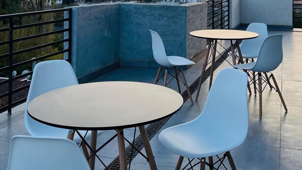 A rooftop terrace with white chairs and tables, offering a view of a cityscape and a distant tower. - Ncomforts Stay inn (Tbilisi)