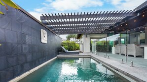 A modern outdoor pool area with a pergola, a glass enclosure, and a seating area with wicker furniture. - Tranquil Beach Side Retreat - Inquire 4 Long Stay Discounts (Mount Coolum)
