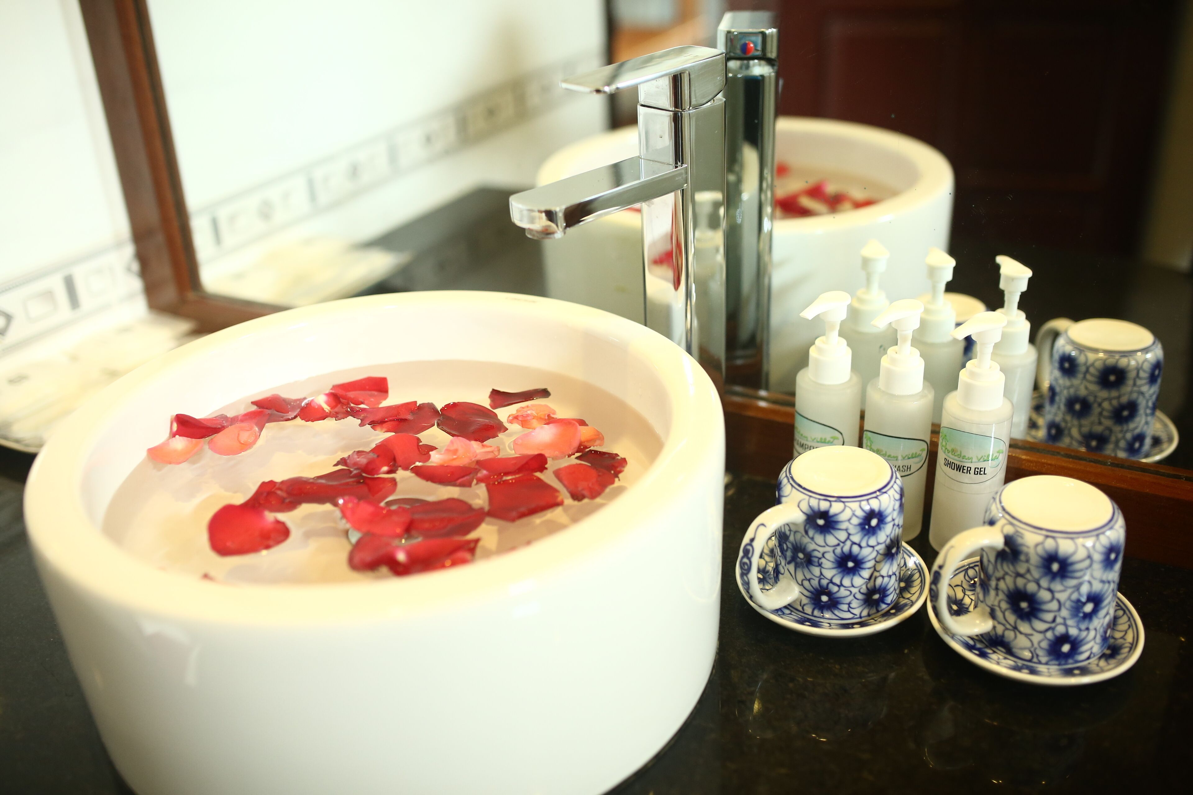 Un lavabo in bagno con petali di rosa, uno specchio e articoli da toilette.