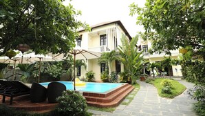 Un espace piscine avec des chaises longues, un sentier et un bâtiment doté d’un balcon.