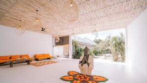Ein Zimmer mit Buddha-Statue, orangenen Sofas und einer gewebten Decke.