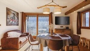 Un salón acogedor con sofá, mesa de comedor, sillas, televisor y un ventanal con vistas.