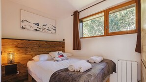 Un dormitorio con cabecera de madera, cama con ropa blanca, un cuadro en la pared y una ventana con cortinas.