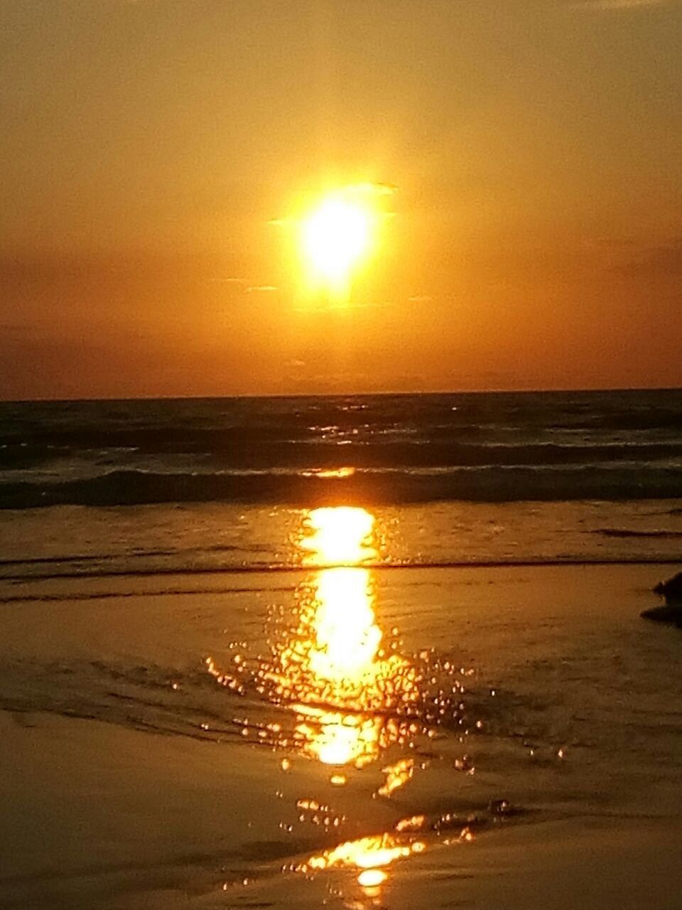 A sunset over the ocean with the sun reflecting on the water.