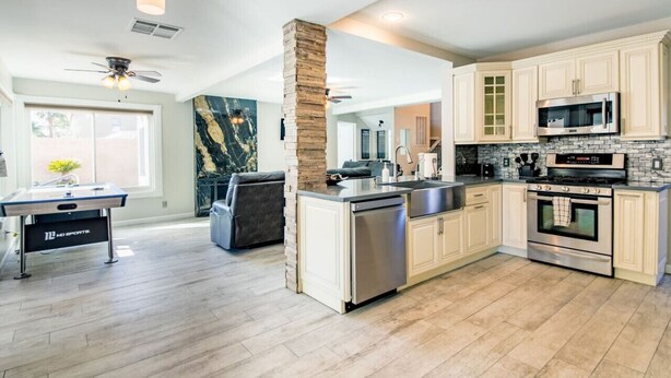 A modern kitchen with white cabinets, a stone pillar, a dishwasher, a microwave, and an oven. - Night at the Roxford 4b 3ba Pool (Las Vegas)